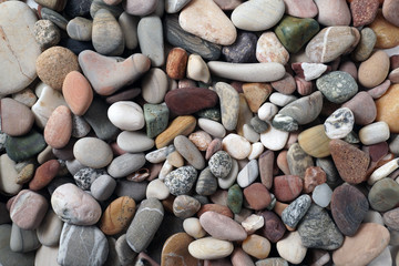 Gravel pattern of colored stones. Abstract nature pebbles background.Small sea stones on the beach, vacation at sea. Top view      