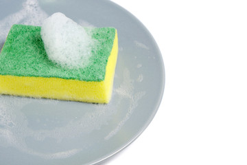 Foam sponge for washing dishes, dirty gray plate on a white background with foam.