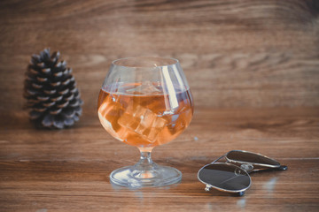 Business composition with glass with delicious whiskey next to aviator lenses. on oak boards
