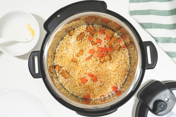 Rice with meat and vegetables prepared in multi cooker, close up on white background, view from above