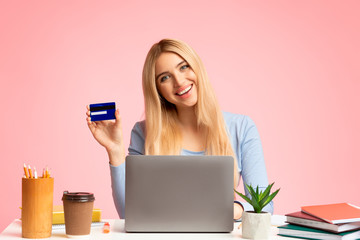 Young woman holding credit card and using laptop