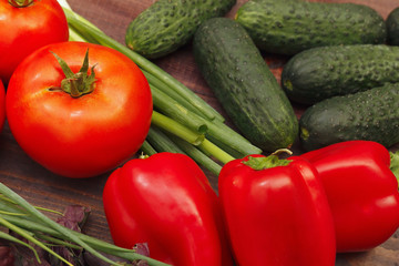 Tomatoes, cucumbers, bellpeppers, and lettuce on a wooden table