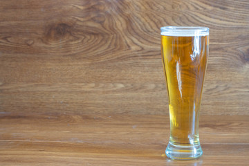 composition of pilsner glass with delicious clear beer on oak boards