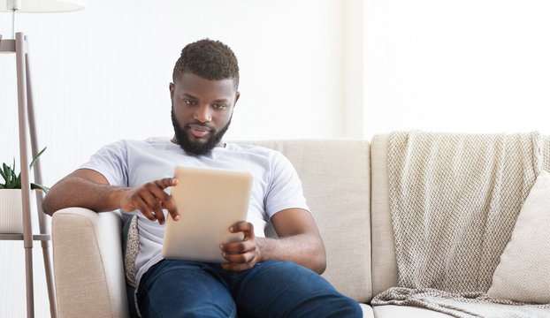 Concentrated African Man Reading News On Digital Tablet