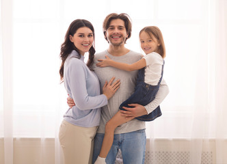 Smiling Mom, Dad And Their Daughter Posing To Camera At Home