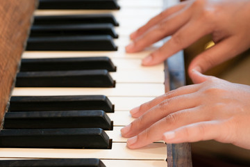 Obraz premium Closeup hand of woman playing old vintage piano. Warm tone.