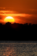 sun falling down on an island with a strange building