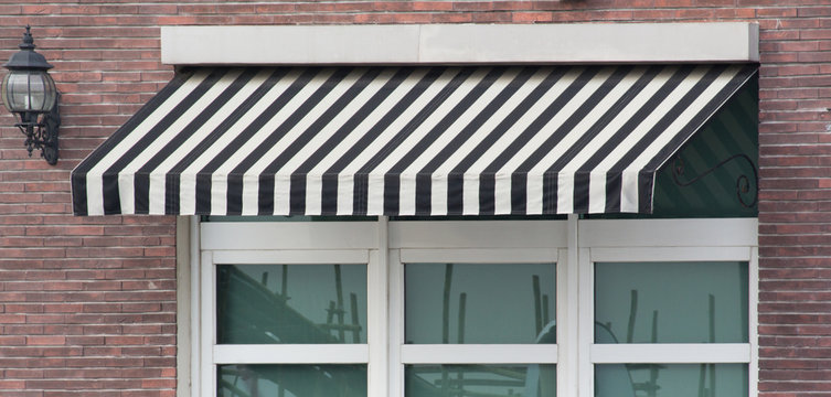black and white striped awning over white window frame of shop.