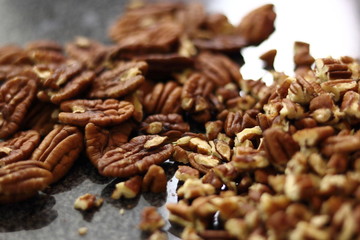 Pecan halves and crushed pecan on granite surface. Making Chocolate, Pear and Pecan Pie Series.