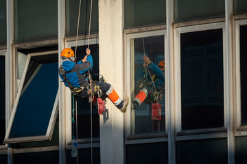 trabajador vertical colgado de una cuerda reparando una fachada ó obrero vertical reparando un...