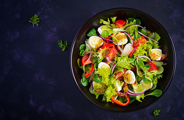 Fresh salad with vegetables tomatoes, red onions, lettuce and quail eggs. Healthy food and diet concept. Vegetarian food. Top view, overhead