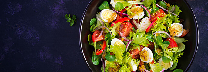 Fresh salad with vegetables tomatoes, red onions, lettuce and quail eggs. Healthy food and diet concept. Vegetarian food. Top view, banner