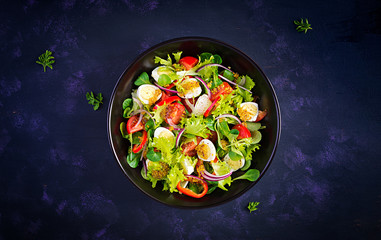 Fresh salad with vegetables tomatoes, red onions, lettuce and quail eggs. Healthy food and diet concept. Vegetarian food. Top view, overhead