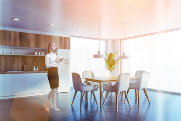 Woman in white and wooden kitchen with table