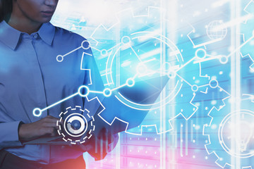 Woman with laptop in data center, gears