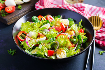 Fresh salad with vegetables tomatoes, red onions, lettuce and quail eggs. Healthy food and diet concept. Vegetarian food.