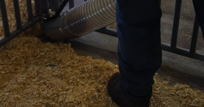 Worker cleaning an animal pen area using an industrial vacuum machine