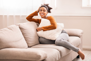 Relaxed Afro Lady Sitting On Couch Hugging Pillow Indoor