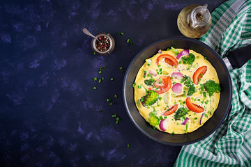 Omelette with broccoli,  tomatoes and red onions in iron skillet. Italian frittata with vegetables. Top view, overhead
