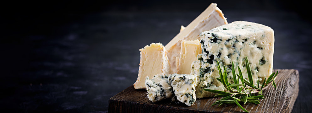 Cheese on wooden boards. Camembert and dorblu on wooden background. Dairy products. Banner