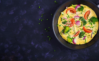 Omelette with broccoli,  tomatoes and red onions in iron skillet. Italian frittata with vegetables. Top view, overhead