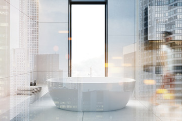 Woman walking in white bathroom with tub and sink