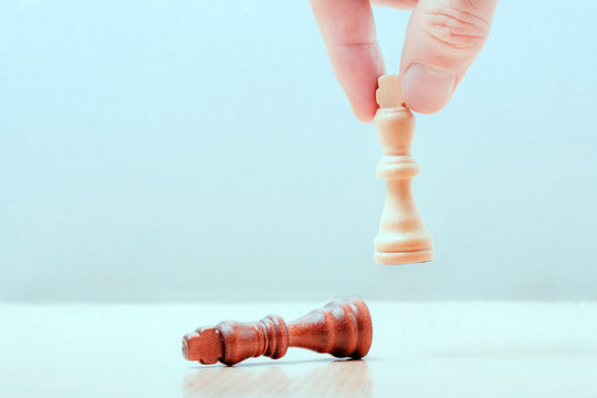 hand puts on the table a white piece of a chess kotol. on the table lies the defeated black king. business success concept..