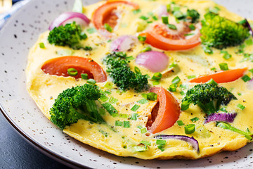 Omelette with broccoli,  tomatoes and red onions on dark table. Italian frittata with vegetables.