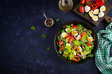 Fresh salad with vegetables tomatoes, red onions, lettuce and quail eggs. Healthy food and diet concept. Vegetarian food. Top view, overhead