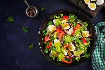 Fresh salad with vegetables tomatoes, red onions, lettuce and quail eggs. Healthy food and diet concept. Vegetarian food. Top view, overhead