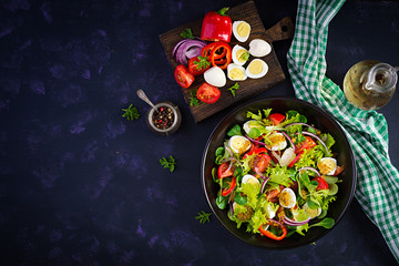 Fresh salad with vegetables tomatoes, red onions, lettuce and quail eggs. Healthy food and diet concept. Vegetarian food. Top view, overhead