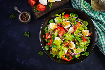 Fresh salad with vegetables tomatoes, red onions, lettuce and quail eggs. Healthy food and diet concept. Vegetarian food. Top view, overhead