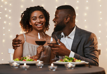 Young afro man and woman having dinner in restaurant