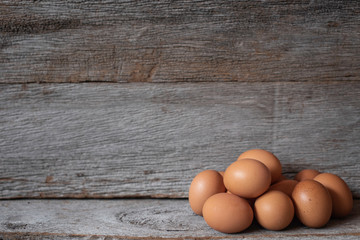 Chicken eggs on the old wood with a wooden wall in the background.