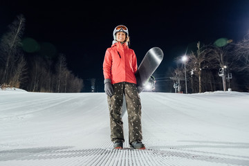 Portrait of female snowboarder at evening slope. Winter sports concept