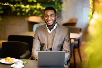 Portrait of handsome black guy looking at camera in bar