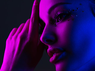 Portrait of the girl is highlighted in bright blue and purple light. Face of a beautiful model....