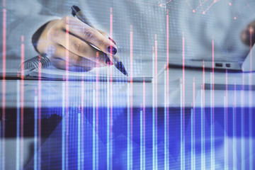 Double exposure of woman's hands making notes with forex graph hologram. Concept technical analysis.