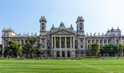 Fototapeta na wymiar Budapest / Hungary - August 29 2019: Facade of the historic luxury building of the Ethnographic Museum in Budapest, Hungary. Ancient building with columns against the blue sky and green city park
