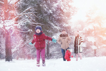 Young family with children are walking in the winter park. Winter walk of parents with children. Walking on a holiday weekend in the winter.