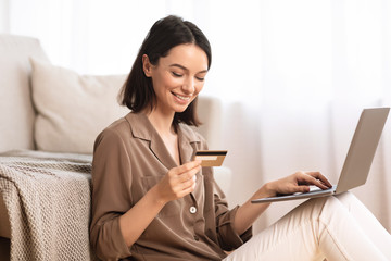 Young woman making purchases sitting on her floor