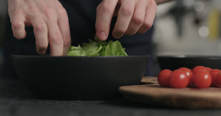man preparing salad tearing frisee leaves