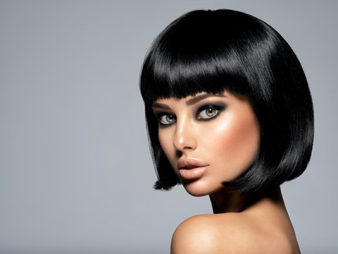 Beautiful fashion woman with a bob hairstyle looks to the camera.  Сloseup face of a sexy fashion model with black gloss make-up,  Attractive white girl with black eye-makeup.  Art.