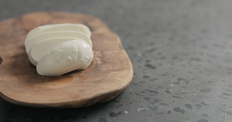 fresh sliced mozzarella cheese on olive wood board