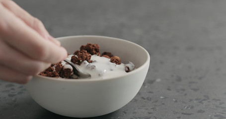 man hand eat chocolate granola with yogurt
