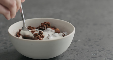 man hand eat chocolate granola with yogurt