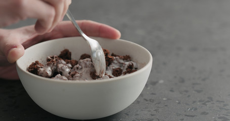 man hand mixing chocolate granola with yogurt