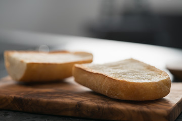 Toasted half of ciabatta for sandwich on olive board