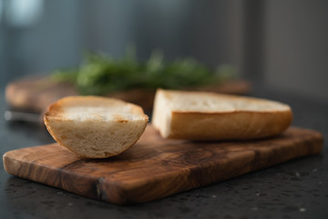 Toasted half of ciabatta for sandwich on olive board