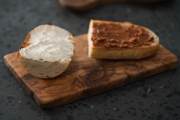 Fototapeta na wymiar Toasted half of ciabatta with cream cheese and red pesto on olive board